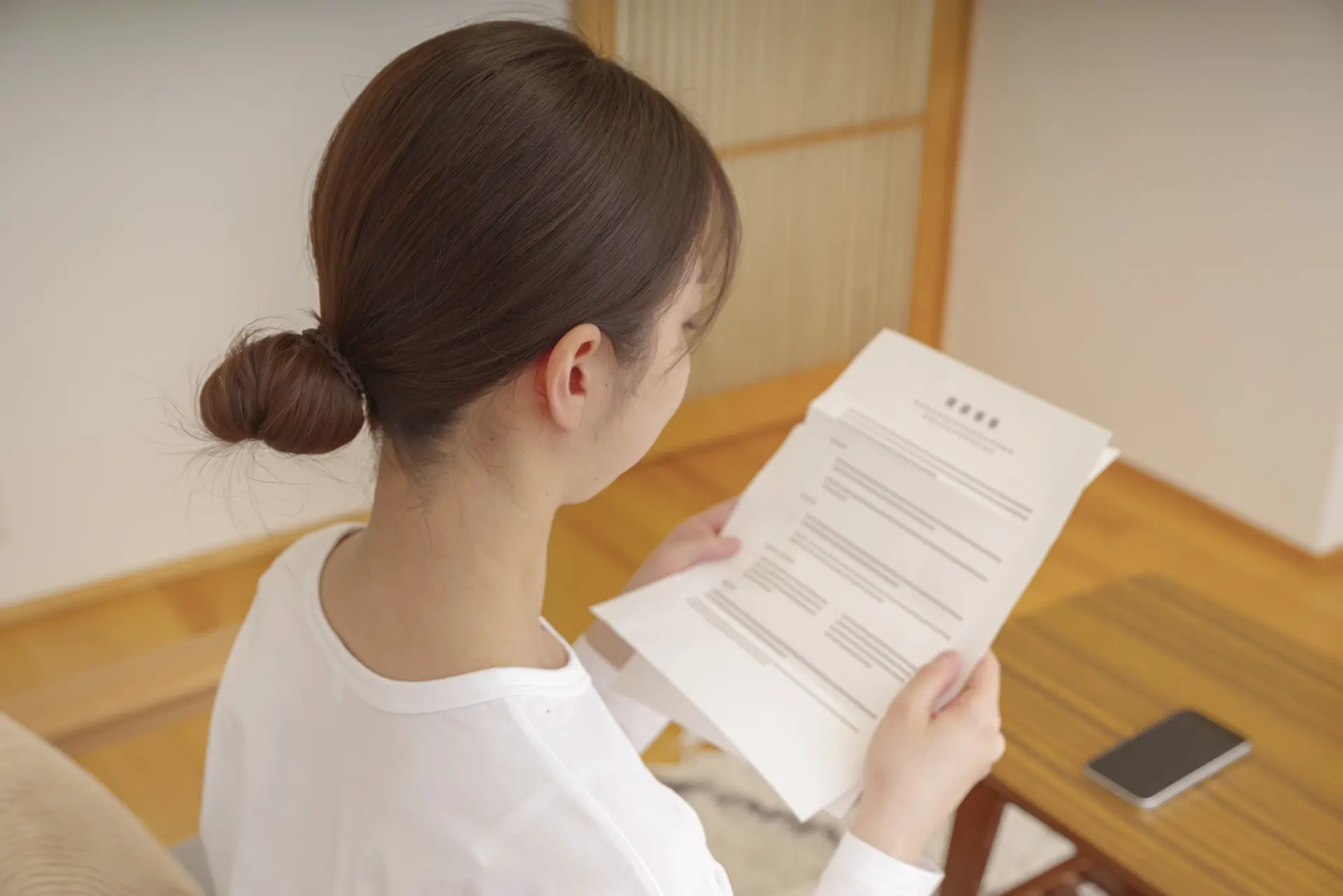 届いた手紙を不安そうに読む女性